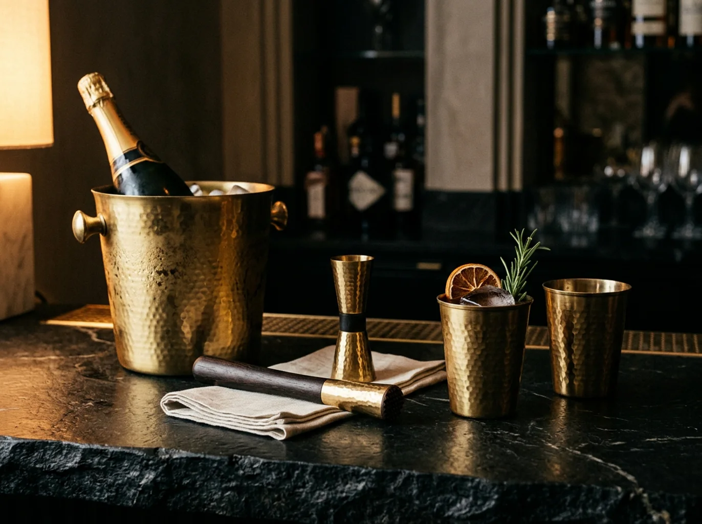 Brass cocktail tools and champagne bucket in a dark editorial bar setting
